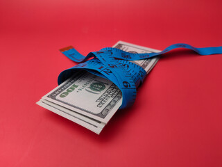 Measuring tape wrapped around dollar bills
