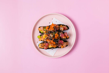 The image is a plate of healthy food on a pink pastel background. The plate is on a table and the...