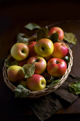 Ripe apples in a basket, with leaves around it