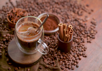 Cup glass of coffee with smoke and coffee beans on old wooden background