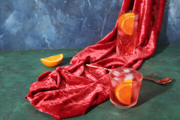 Glasses of tasty Negroni cocktail and fabric on color background