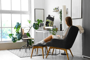 Young woman sitting on armchair in office