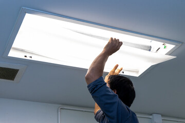 Technician holding recessed mounted luminaire in ceiling house to repair or maintenance and fixing. Office building or house problem from electric light lamp for repairman change fluoresce light.