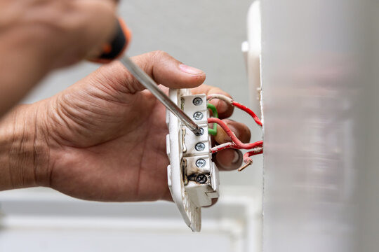 Close-up hand of electrician holding electric outlet plug for repair or maintenance and fixing in office room. Dangerous of electric spark from short circuits and fire in house.
