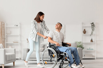 Young woman and her husband in wheelchair at home