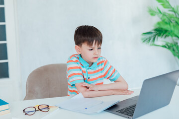 Boy sitting at table looking at laptop