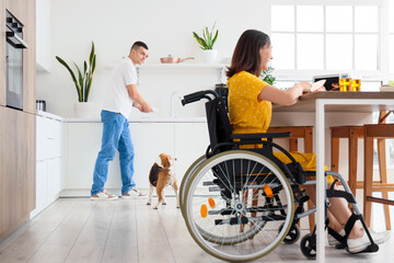 Young man with Beagle dog and his wife in wheelchair at home