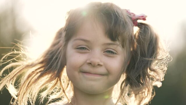 Happy girl in the sun in wind. Close-up of the girl face in the park. Dream girl. Hair in the wind. The child smiles at the camera. Girl's dream. Face close-up. Happy child in the park. Beautiful face