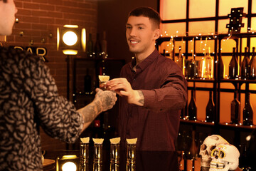 Young men with tequila shot in bar at night