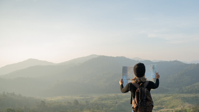 Adventurous girl navigating in with a topographic map in beautiful mountains of thailand. woman wearing hat stand alone and enjoying freedom and calm inspired travelling on background view mockup.