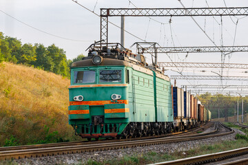 Green powerful locomotive pulls freight train. Freight railway transportation.