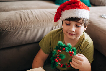 Kid boy decorating Christmas tree put off balls from the box authentic real celebration image lifestyle. Xmas with family children fun at cozy home