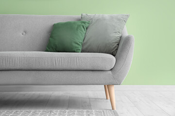 Grey sofa with cushions near green wall in room