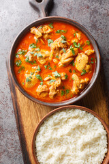 Traditional spicy Lahori Chicken Curry served with rice closeup on the wooden board on the table. Vertical top view from above