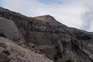 Severe mountain landscape. View of the top of the volcano. Rocks on the rim of a volcanic crater. Travel, tourism and hiking on the Kamchatka Peninsula. Gorely volcano, Kamchatka Territory, Russia.