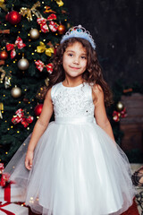 Little girl at christmas tree with gifts and toys for new year