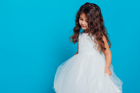 Beautiful little girl in white dress on blue background