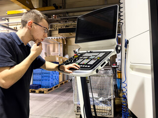 A new worker is looking for the right button to turn on a CNC milling machine.