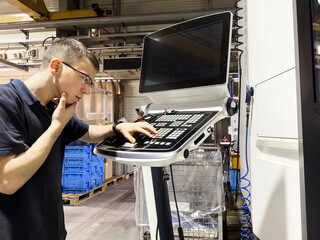 Pensive and inexperienced worker looking for the right button on a cnc milling machine