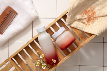 Fototapeta na wymiar Comb, towel and body care products are placed in a wooden box on the white square tile floor. Pink salt is a popular natural ingredient used to exfoliate the skin.