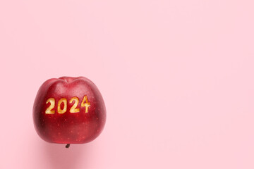 Ripe apple with with carved figure 2024 on pink background