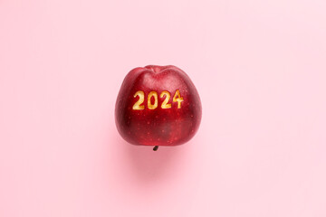 Ripe apple with with carved figure 2024 on pink background