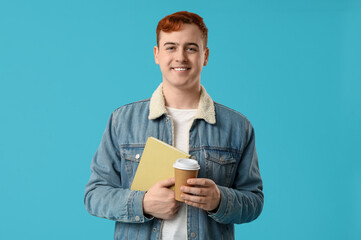 Young man holding book and cup of coffee on color background