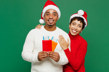 Traveler fun couple man woman wear red casual clothes hold passport ticket isolated on plain green background. Tourist travel abroad in free spare time rest getaway. Air flight trip journey concept.