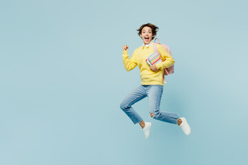 Full body side view young excited woman student wear casual clothes sweater hold backpack bag jump high run fast hold books isolated on plain blue background. High school university college concept.