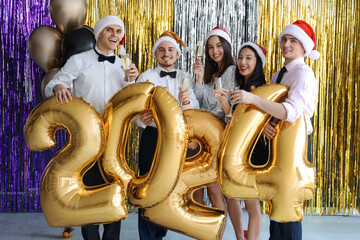Group of friends with champagne and figure 2024 at New Year party