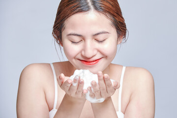 Smiling young woman washing foam face by natural foamy gel. satisfied girl with bare shoulders applying cleansing beauty product on cheeks. personal hygiene, skincare daily routine.