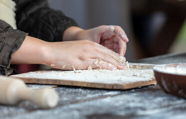 A woman kneads the dough with her hands