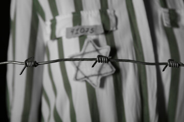 Jewish female prisoner behind barbed wire on dark background, closeup. International Holocaust Remembrance Day