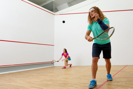 Happy millennial-age couple characters playing game of racquetball together