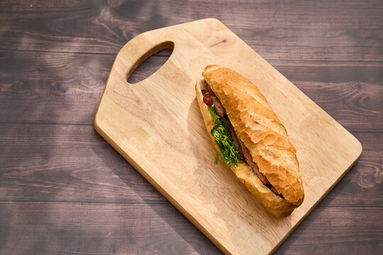 Banh Mi Heo Quay.Vietnamese bread with roasted pork and fresh herbs as scallions, coriander, carrot, cucumber, chilli