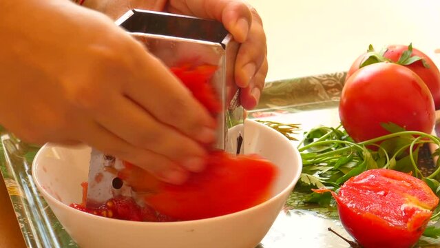 Detail of female hands grated tomato for typical Valencian paella "sofrito.