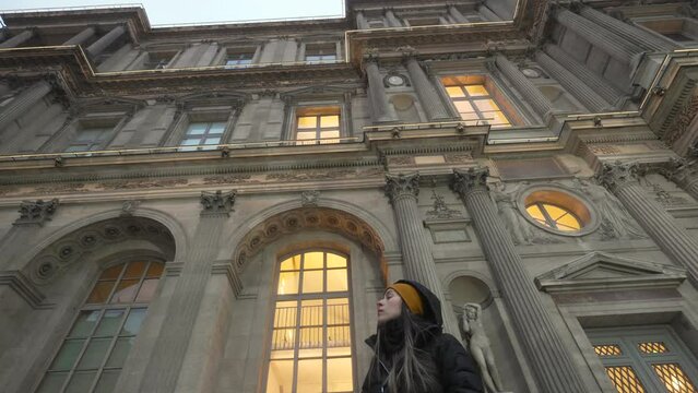 Young tourist woman admiring Louvre museum facade, Paris. Low angle shot