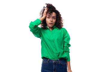 young caucasian lady with black curls dressed in a green blouse posing against a white background