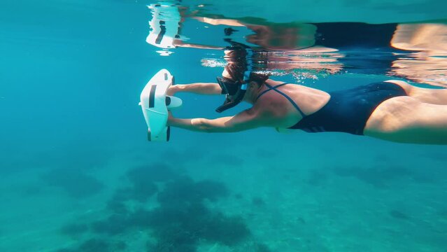 Underwater scooter. Woman swims using modern innovative diving gadget.