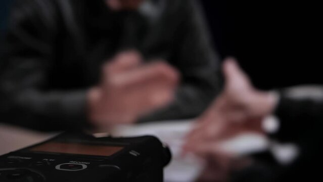 Digital voice audio recorder, close up blinking rec button. Interrogation by police officer detective. FBI agent shows evidence knife and photo of crime scene. Suspect denies accusations of his guilt
