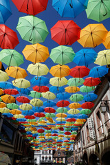 Fototapeta na wymiar Colorful umbrellas over the main street in L' Aigle, Orne, France