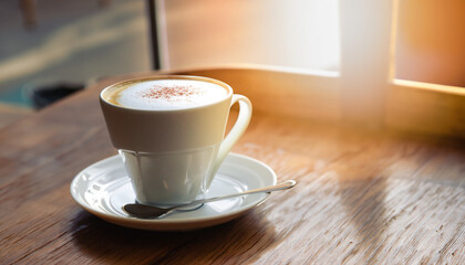 Obraz premium hot coffee cup in coffee shop with sunlight on wooden table