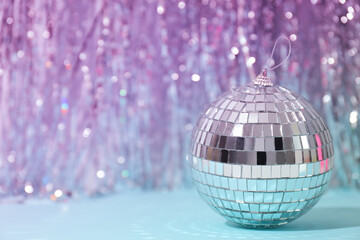 Disco ball with festive silver ribbons on blue background