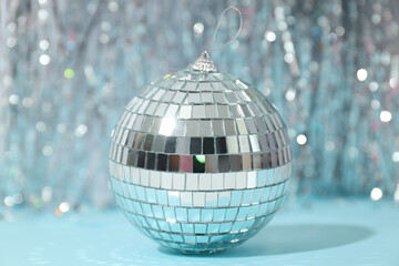 Disco ball with festive silver ribbons on blue background