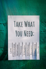 White tear-off stub note with text 'Take what you need' on emerald wall.