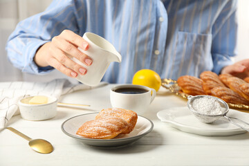 Madeleine cakes, butter, flour and milk jug in hand on light background