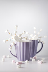 A purple mugs with hot coffee and marshmallows. Two cups with marshmallows in snowflake shapes.
