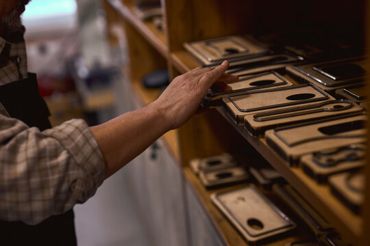 old craftsman putting leather phone cases on the shelf. close up cropped side view photo, trade, business, lifestyle, handmade present, gift,man selling leather phone cases, sale - Powered by Adobe