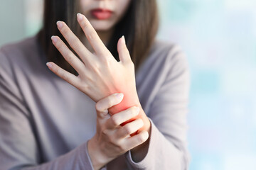 A woman squeezes a wrist that is inflamed due to arthritis. - obrazy, fototapety, plakaty