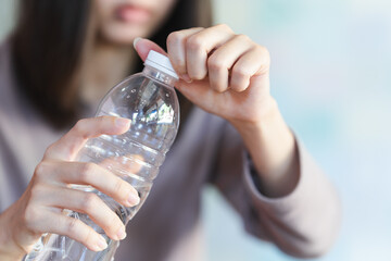 Women holding drinking bottle and opening the cap of a water bottle to drink water.